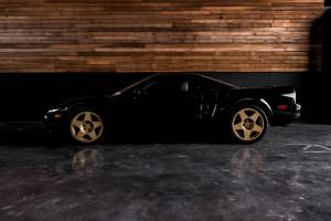 Black 1991 Acura NSX drivers side with a wood wall backdrop