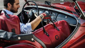 man with red luggage set in classic car