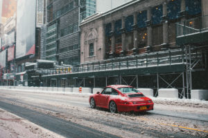 Porsche driving on a snowy city street