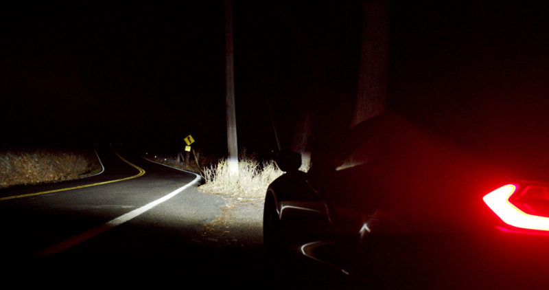 Photo of a car pulled over to teh side of a road at night