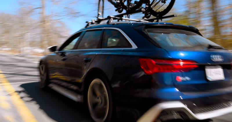 Photo of a car with bike on top driving on a road